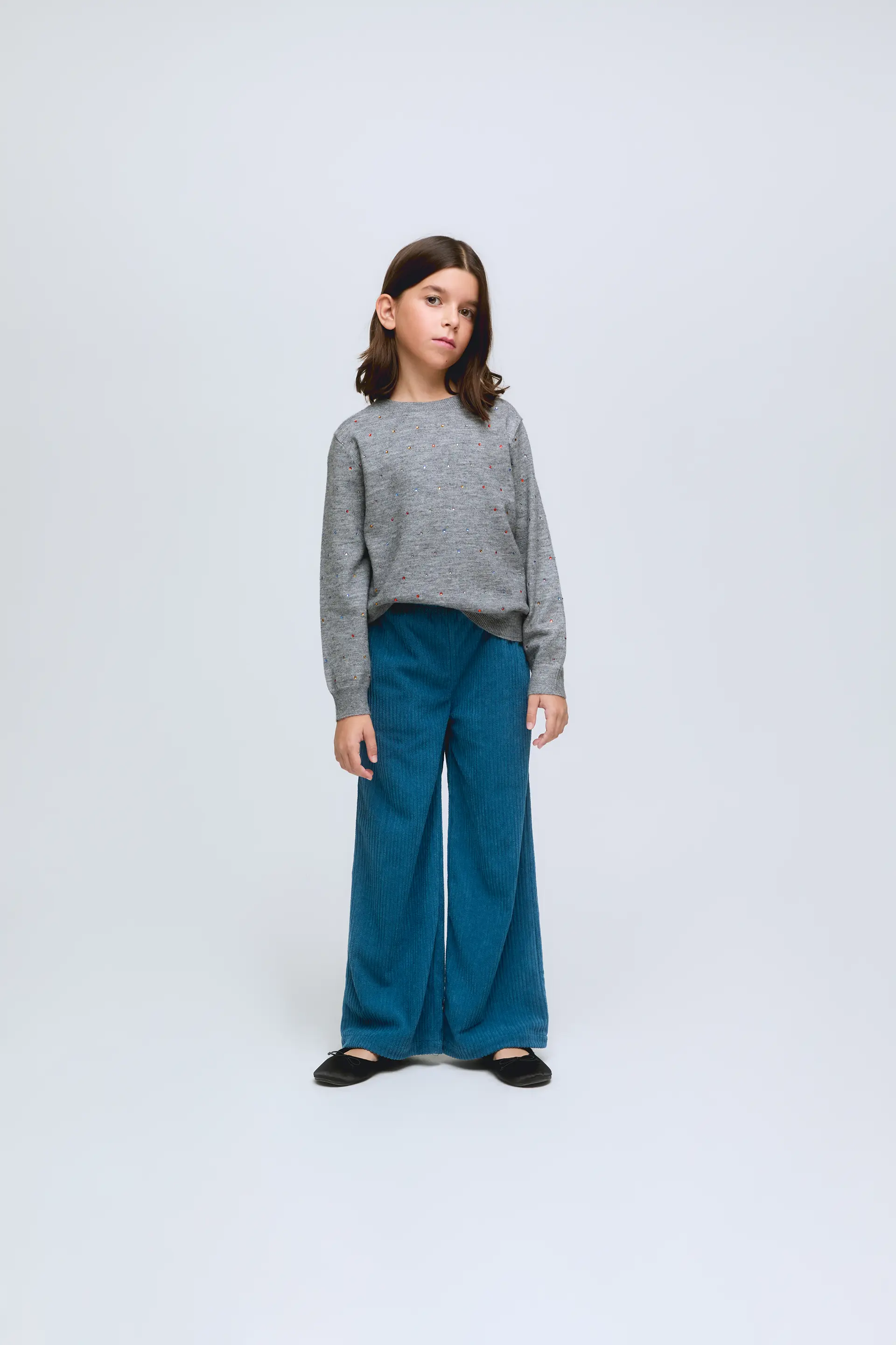 Jersey de niña de punto gris con pequeños apliques de brillos.